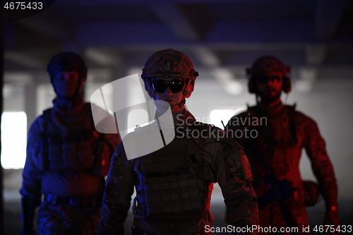 Image of soldier squad team walking in urban environment colored lightis