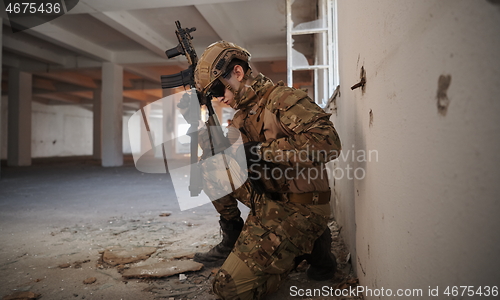 Image of soldier in action near window changing magazine and take cover