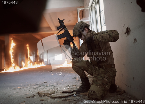 Image of soldier in action near window changing magazine and take cover