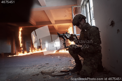 Image of soldier in action near window changing magazine and take cover