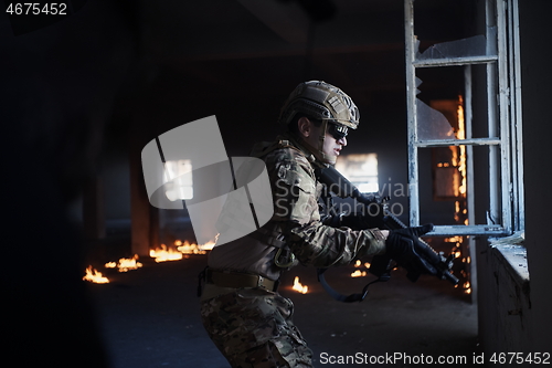 Image of soldier in action near window changing magazine and take cover