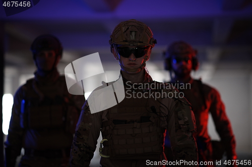 Image of soldier squad team walking in urban environment colored lightis