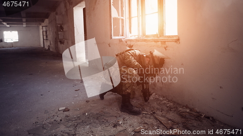 Image of soldier in action near window changing magazine and take cover