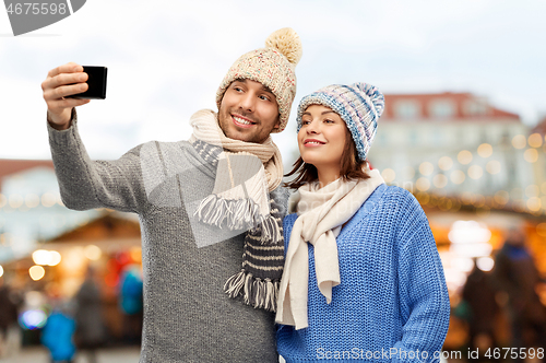 Image of couple takes selfie by smartphone christmas market