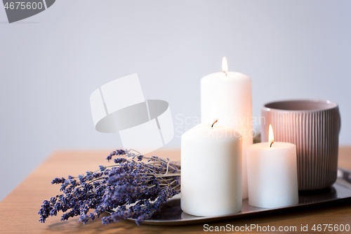 Image of candles, tea in mug and lavender flowers on table