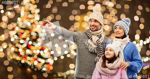 Image of happy family in winter hats over christmas lights