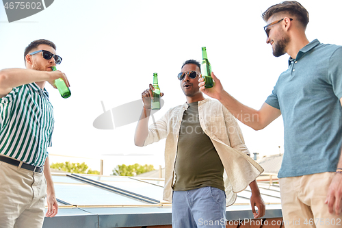 Image of happy male friends drinking beer at rooftop party