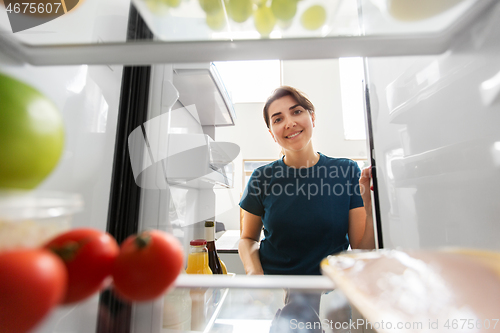 Image of happy woman at open fridge at home kitchen