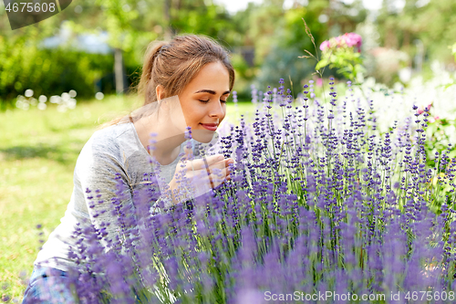 Image of young woman smelling lavender flowers in garden