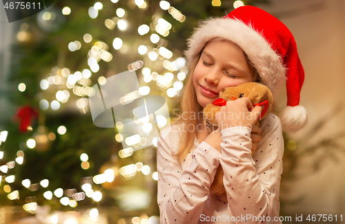 Image of smiling girl in santa hat with christmas gift