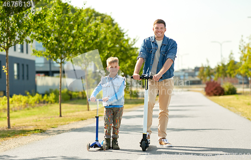 Image of father and little son riding scooters in city