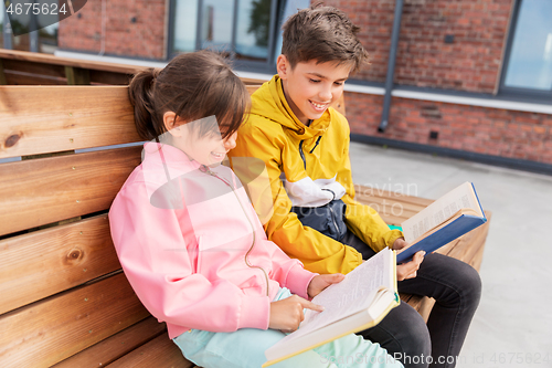 Image of school children reading books sitting on bench