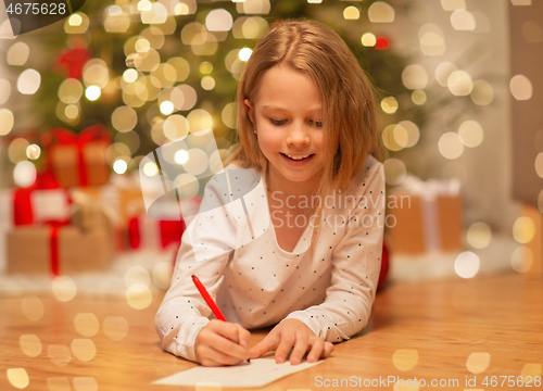 Image of smiling girl writing christmas wish list at home