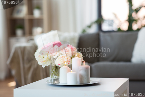 Image of candles burning on table and flowers at cozy home