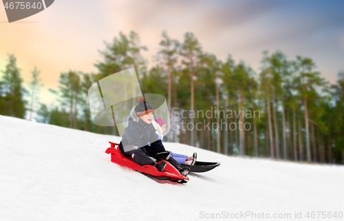 Image of happy kids sliding on sleds down hill in winter