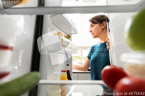 Image of woman at open fridge at home kitchen