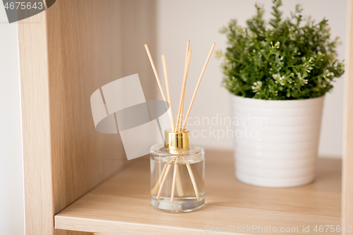 Image of aroma reed diffuser and pot flower on wooden shelf