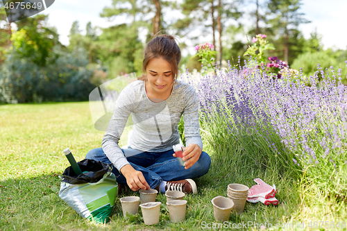 Image of woman planting seeds to pots at summer garden