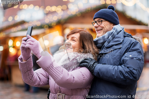 Image of senior couple taking selfie at christmas market