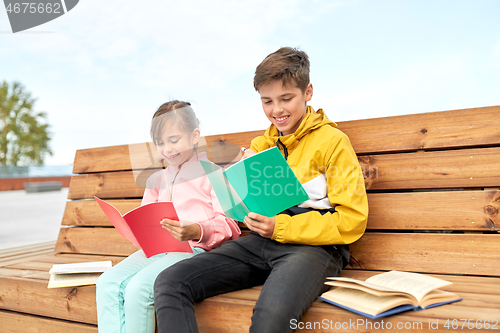 Image of school children with notebooks sitting on bench