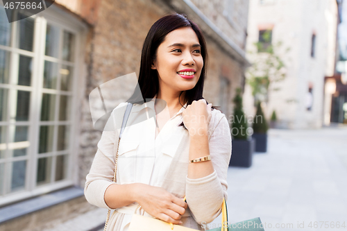 Image of asian woman with shopping bags walking in city