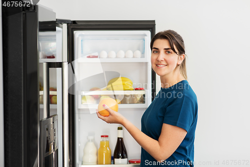 Image of happy woman taking food from fridge at home