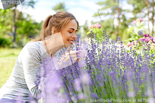 Image of young woman smelling lavender flowers in garden