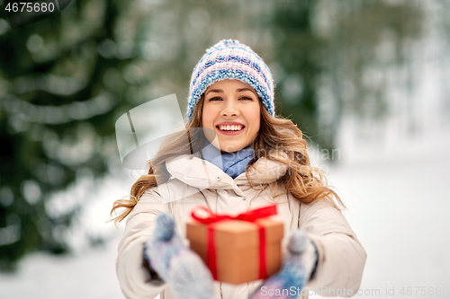 Image of happy young woman with christmas gift in winter