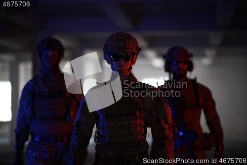 Image of soldier squad team walking in urban environment colored lightis