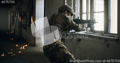 Image of soldier in action near window changing magazine and take cover