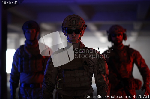 Image of soldier squad team walking in urban environment colored lightis