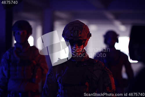 Image of soldier squad team walking in urban environment colored lightis