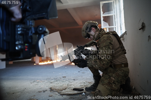 Image of soldier in action near window changing magazine and take cover