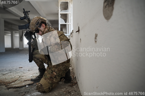 Image of soldier in action near window changing magazine and take cover