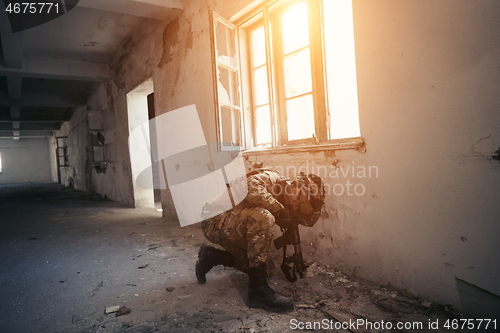 Image of soldier in action near window changing magazine and take cover