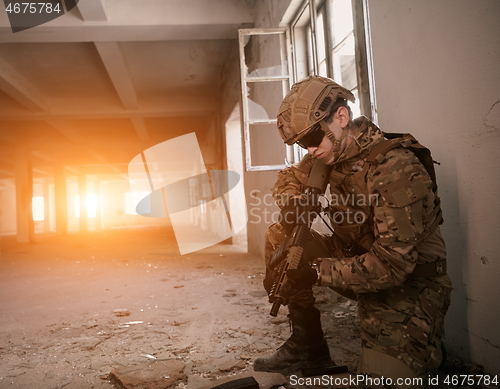 Image of soldier in action near window changing magazine and take cover