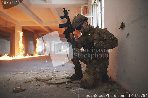 Image of soldier in action near window changing magazine and take cover