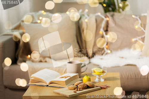 Image of oat cookies, book, tea and lemon on table at home