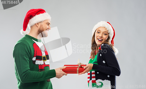 Image of happy couple in christmas sweaters with gift box