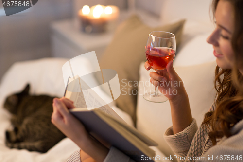 Image of happy young woman reading book in bed at home