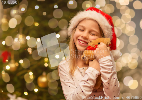 Image of smiling girl in santa hat with christmas gift