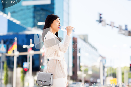 Image of asian woman drinking water from bottle in city