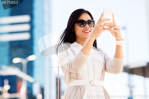 Image of asian woman taking selfie by smartphone in city