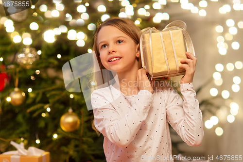 Image of smiling girl with christmas gift at home