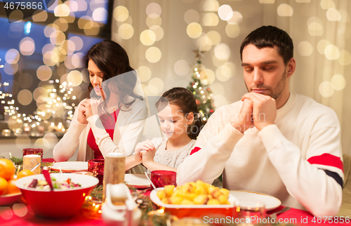 Image of family praying before meal at christmas dinner