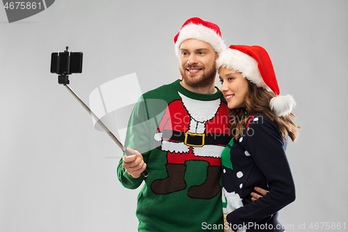 Image of happy couple in christmas sweaters taking selfie