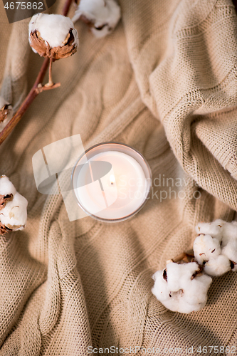 Image of burning candle and cotton flower on blanket