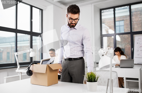 Image of sad fired male office worker with personal stuff