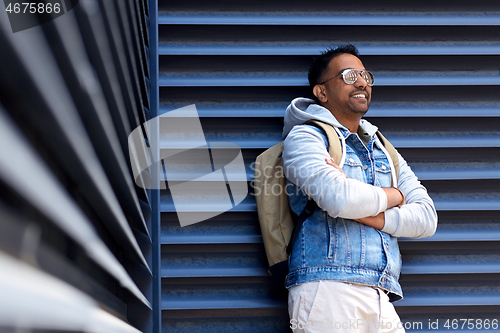 Image of smiling indian man with backpack on city street