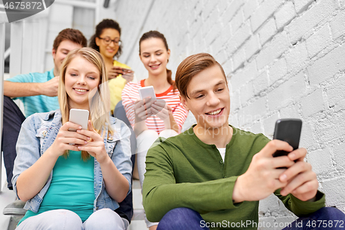 Image of students with smartphones sitting on stairs